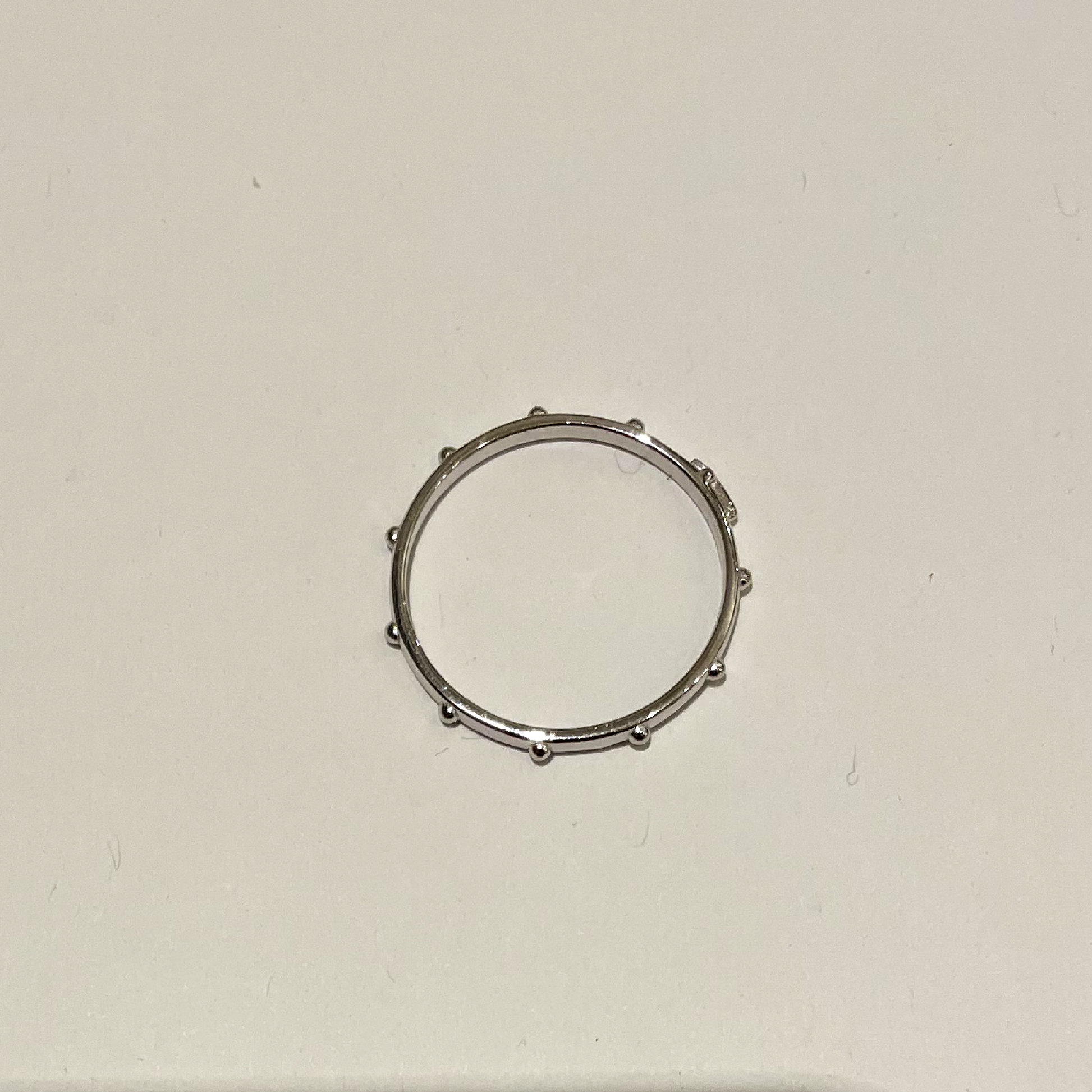 Simple thin silver ring with 11 bulging dots on the environment of the ring.
