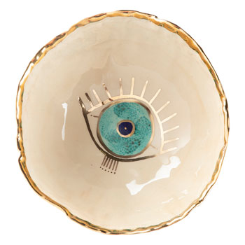 Beige ceramic bowl with golden edge and Eye design on it.