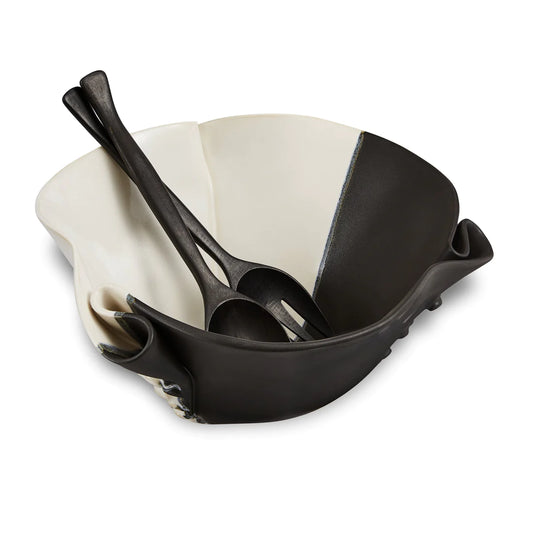 Irregular black and beige ceramic bowl with texture in outside of the bowl and black wooden spoon and fork.