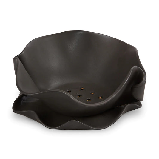 Irregular black ceramic bowl with holes on the bottom.