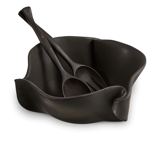 Irregular black ceramic bowl with black wooden spoon and fork.