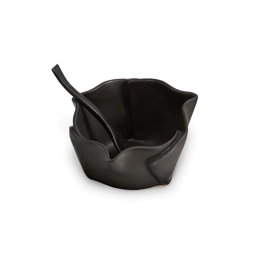 Irregular black ceramic bowl with black wooden spoon.