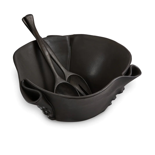 Irregular black ceramic bowl with texture in outside of the bowl and black wooden spoon and fork.