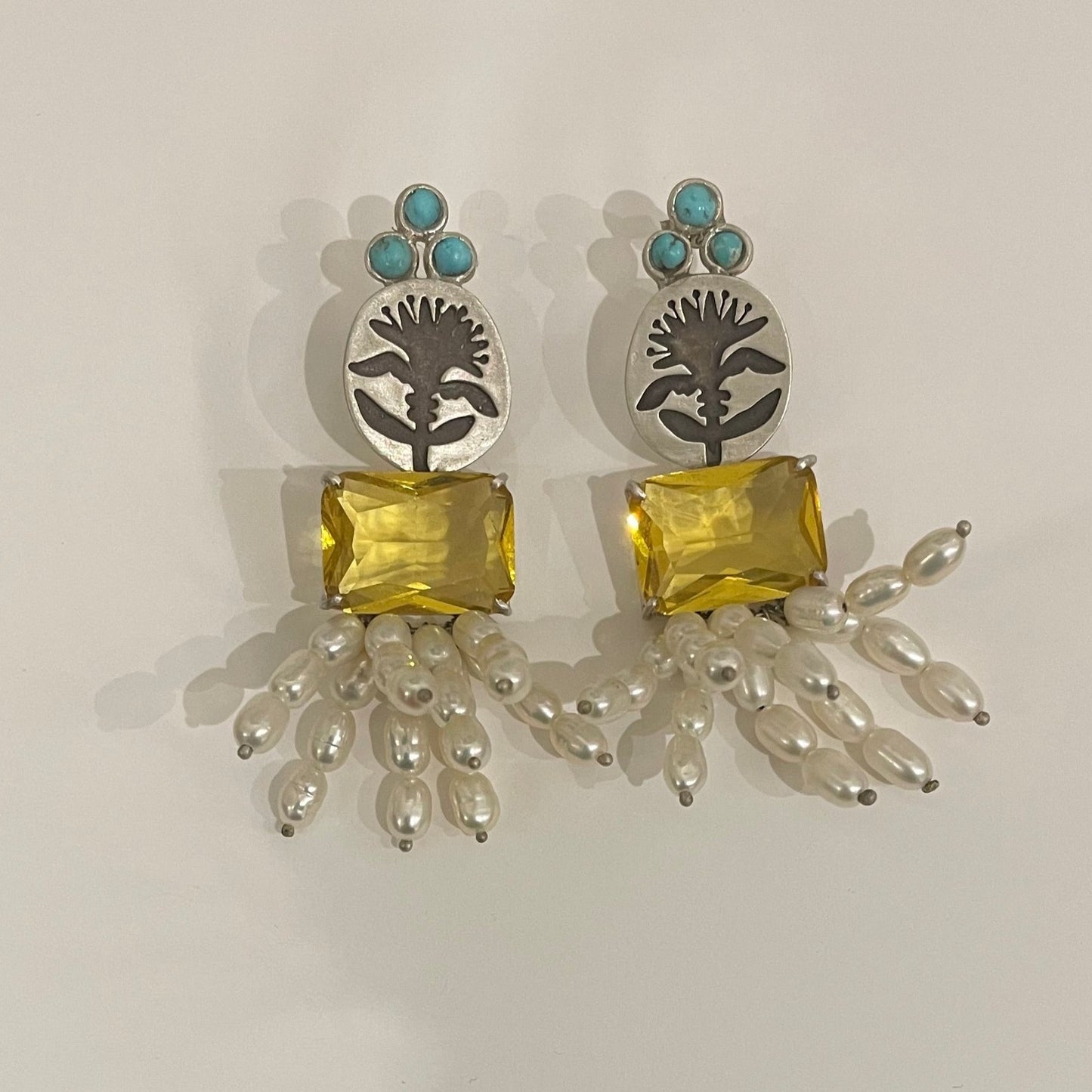 Silver earrings with three round turquoises on the top, and square yellow crystal and Pearls on the bottom.