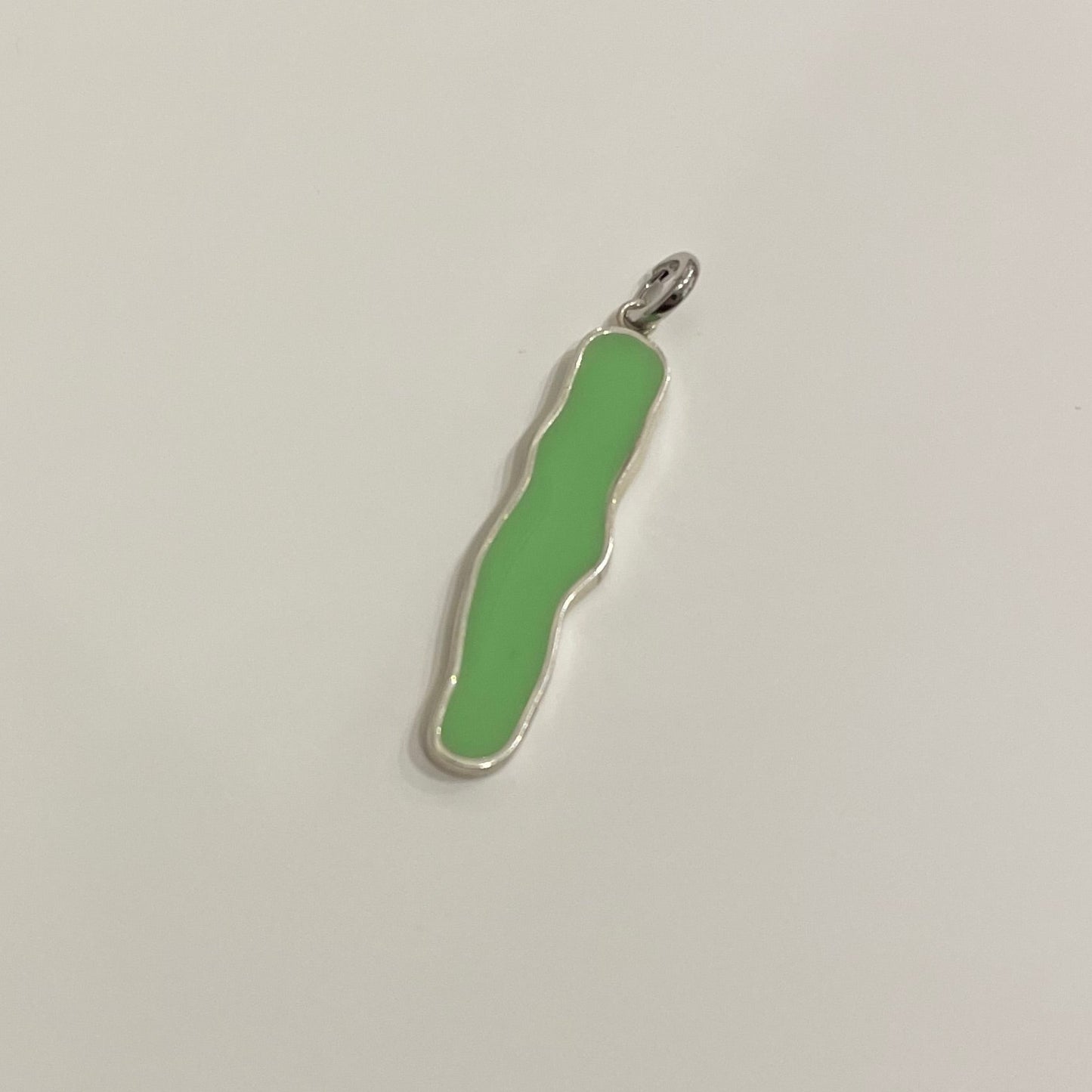 Long irregular shape clip-on charm made by silver and filed by green epoxy resin.
