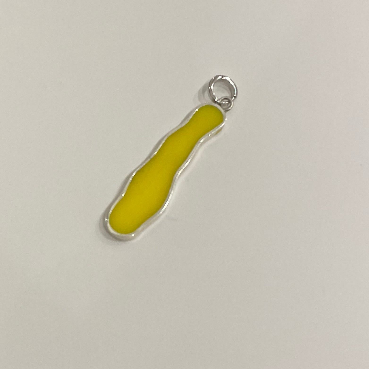 Long irregular shape clip-on charm made by silver and filed by yellow epoxy resin.