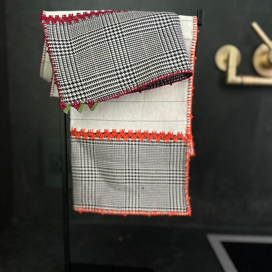 Napkin in white and black with orange and red embroidery. 