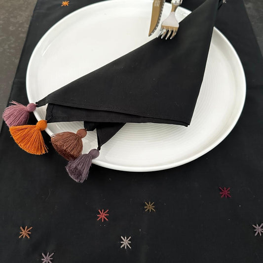 Black rectangle napkin with colorful stars embroidered on it.