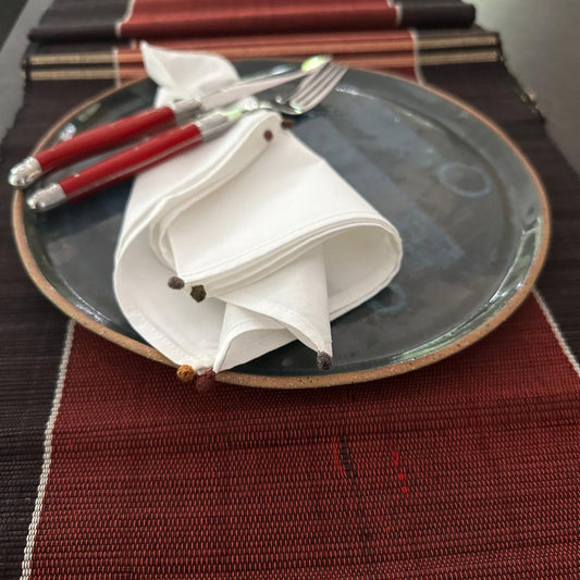 White napkin on a plate and the plate is on red and black runner