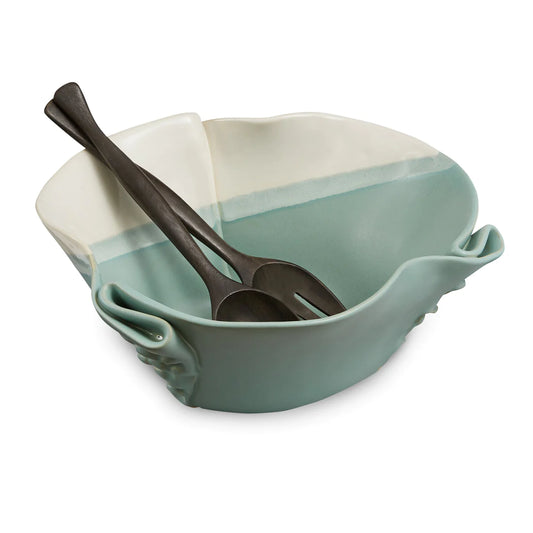 Irregular green and beige ceramic bowl with texture in outside of the bowl and black wooden spoon and fork.