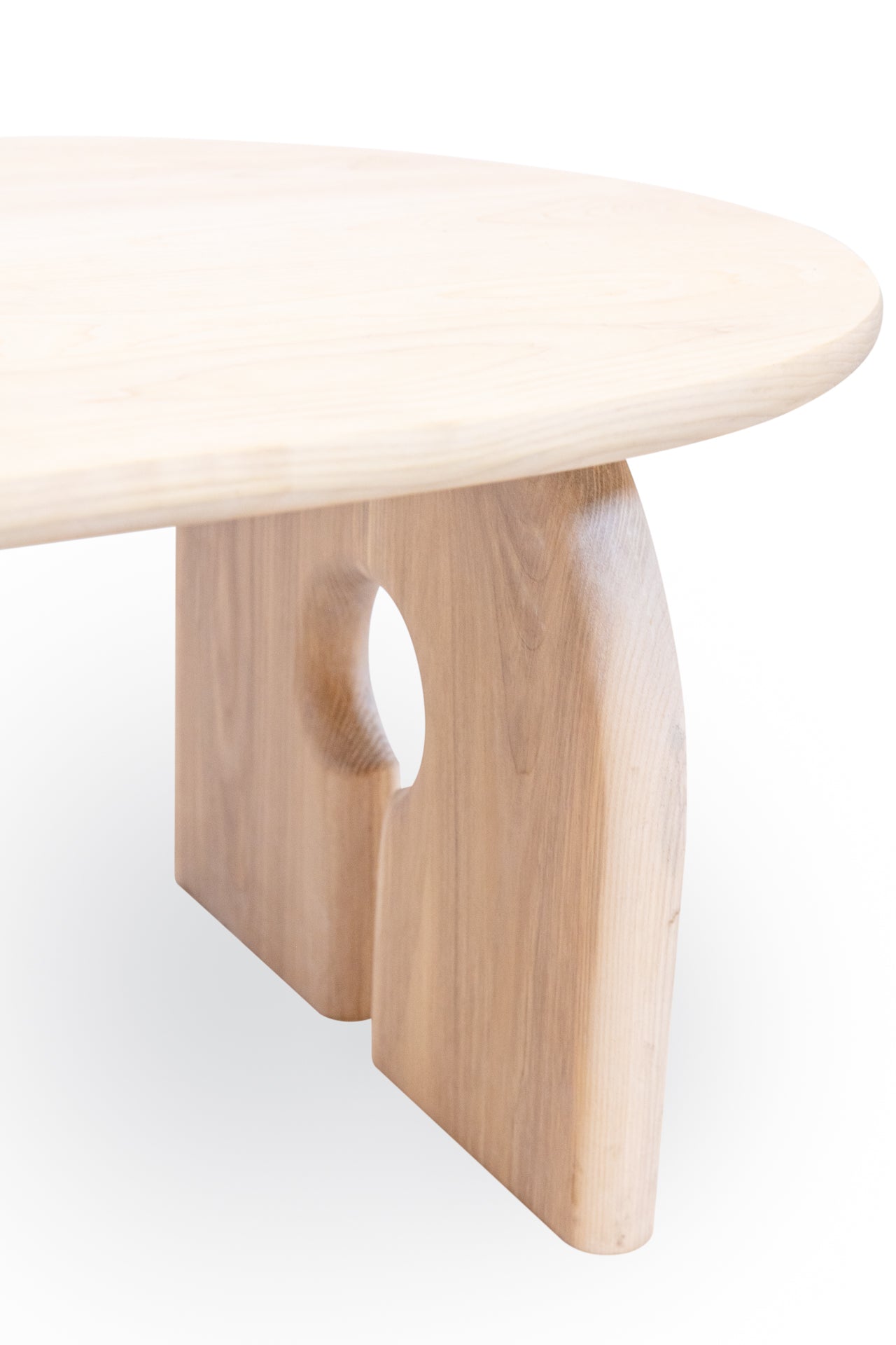 Wooden coffee table with a natural finish, featuring a fully curved edge and corners. The table has two legs positioned on opposite sides, each shaped like a half-circle connected to the table from the top of the circle.