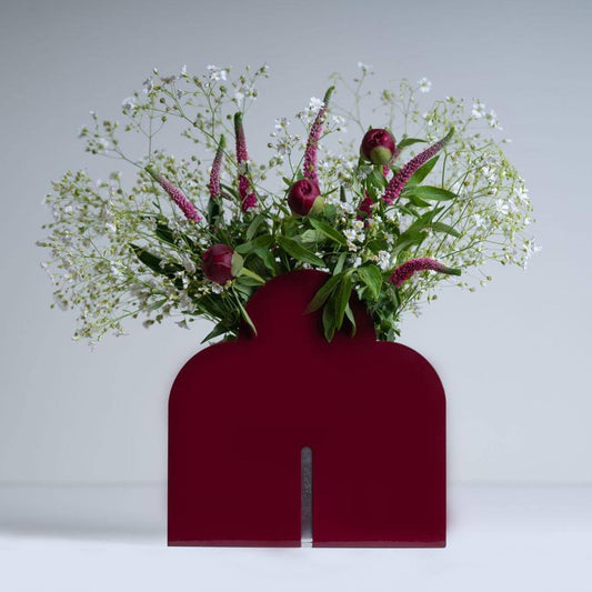 Red metal vase including two parallel sheet which has three arcs on the top. there is  a pot between the two sheets for holding flowers.