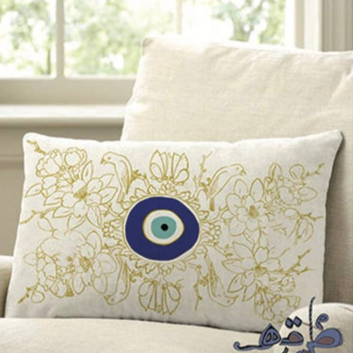 cushion with yellow birds and flowers, and the evil eye in the center.