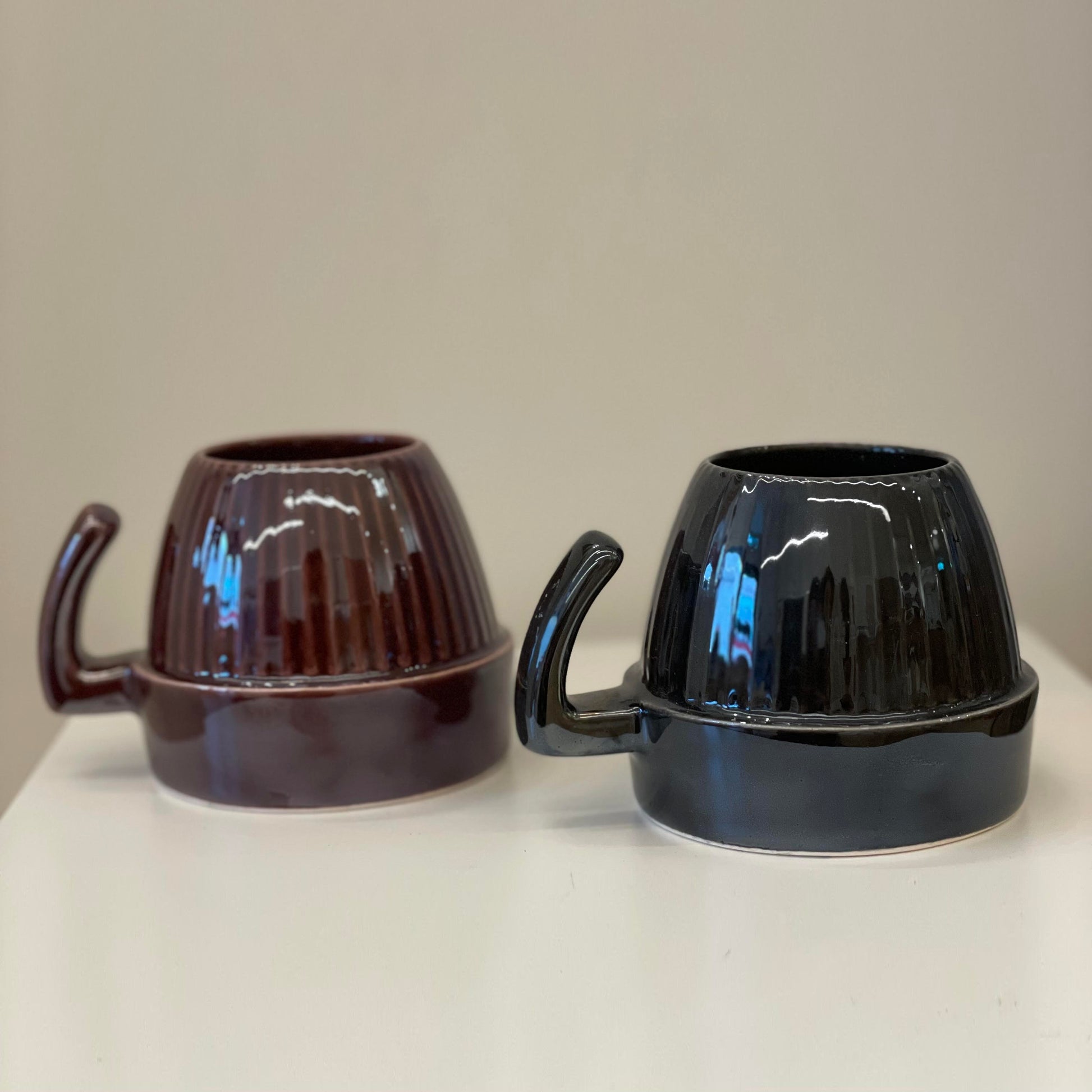 Two ceramic mugs in dark colors.